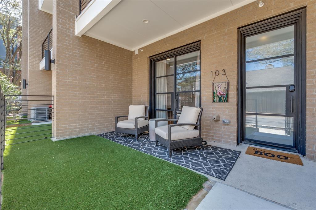 Covered patio with brick exterior, artificial turf, and a concrete walkway