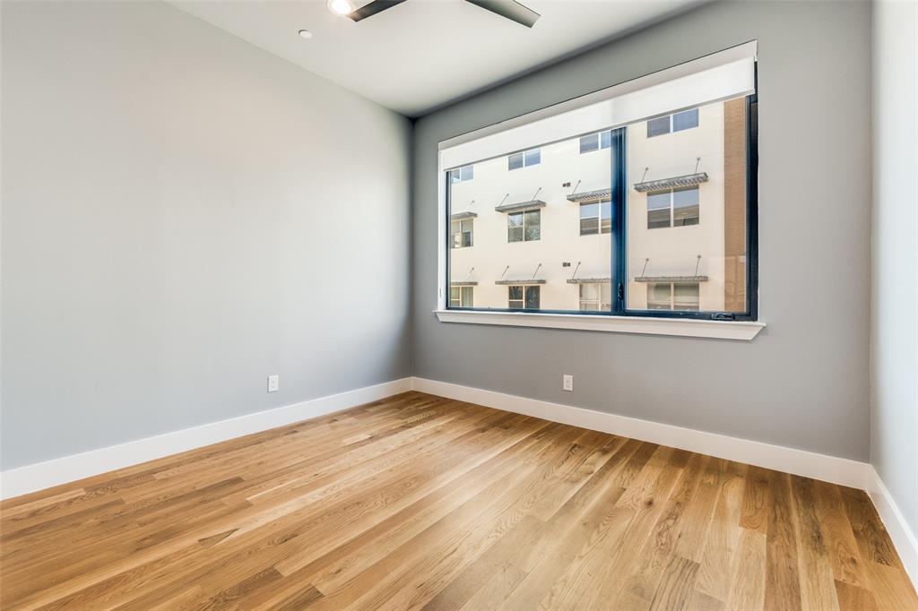 Light-filled room featuring wood-finish flooring, a contemporary ceiling fan, and a wide window with white trim