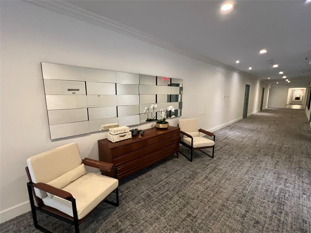 Hallway with crown molding, recessed lighting, wall-to-wall carpeting, and a decorative mirror installation