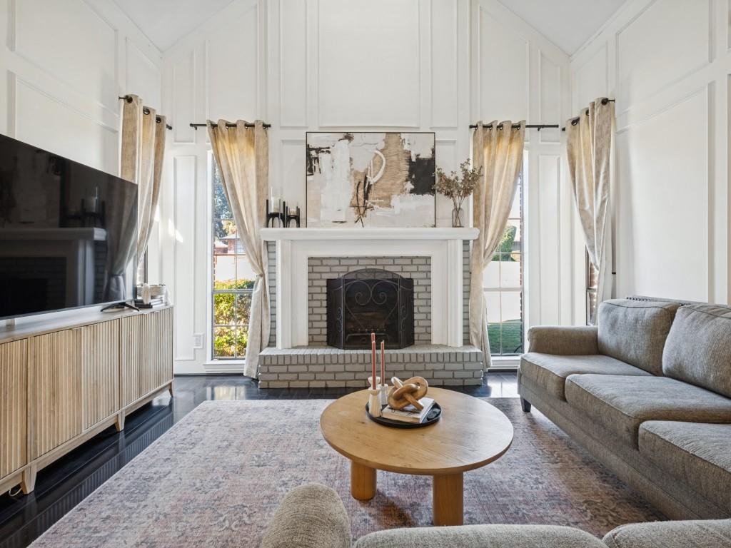 Vaulted ceilings with floor-to-ceiling wainscoting, fireplace with a painted brick surround and wood mantel, and dark-toned flooring Vaulted ceilings with floor-to-ceiling wainscoting, fireplace with a painted brick surround and wood mantel, and dark-toned flooring