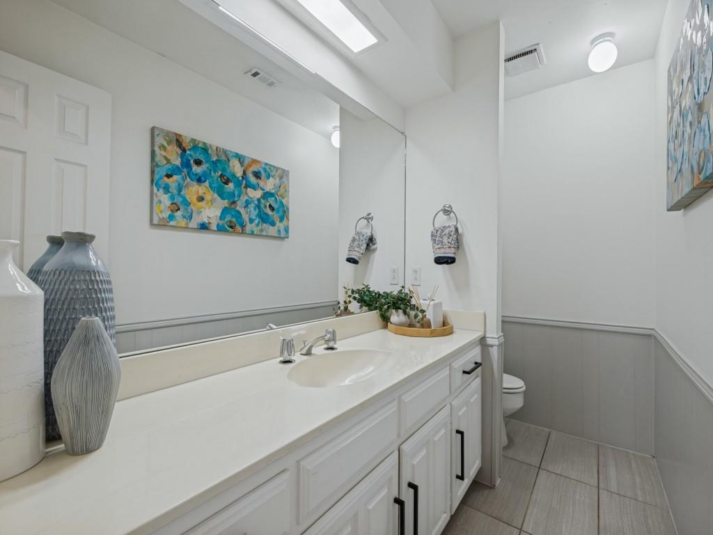 Bathroom featuring a vanity with a light-toned countertop, under-mount sink, matte black hardware, floor-to-ceiling mirror, and ceramic tile flooring