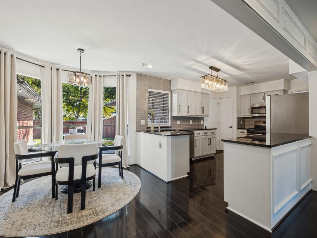 Kitchen featuring wood-finish flooring, shaker-style cabinetry, a peninsula with stone-surface countertops, and rectangular tile backsplash Kitchen featuring wood-finish flooring, shaker-style cabinetry, a peninsula with stone-surface countertops, and rectangular tile backsplash