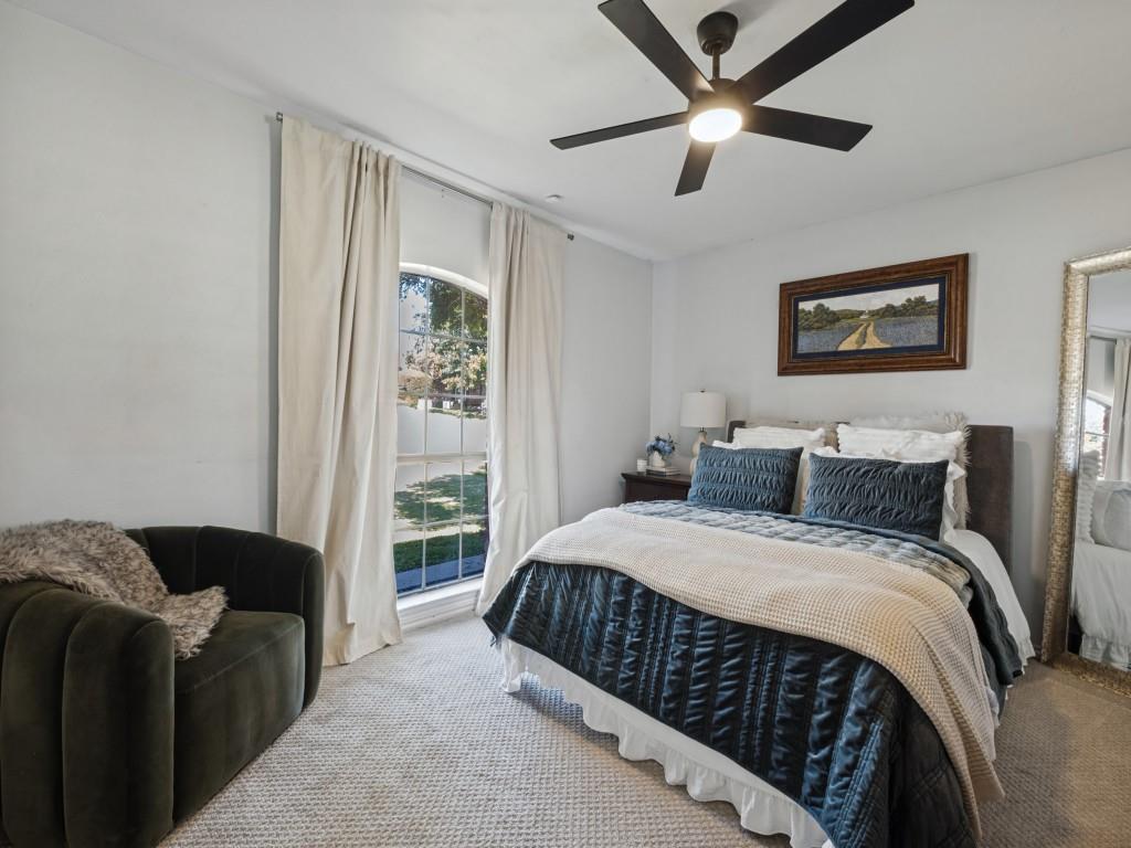 Arched window, neutral wall-to-wall carpeting, and a modern black multi-blade ceiling fan with integrated lighting