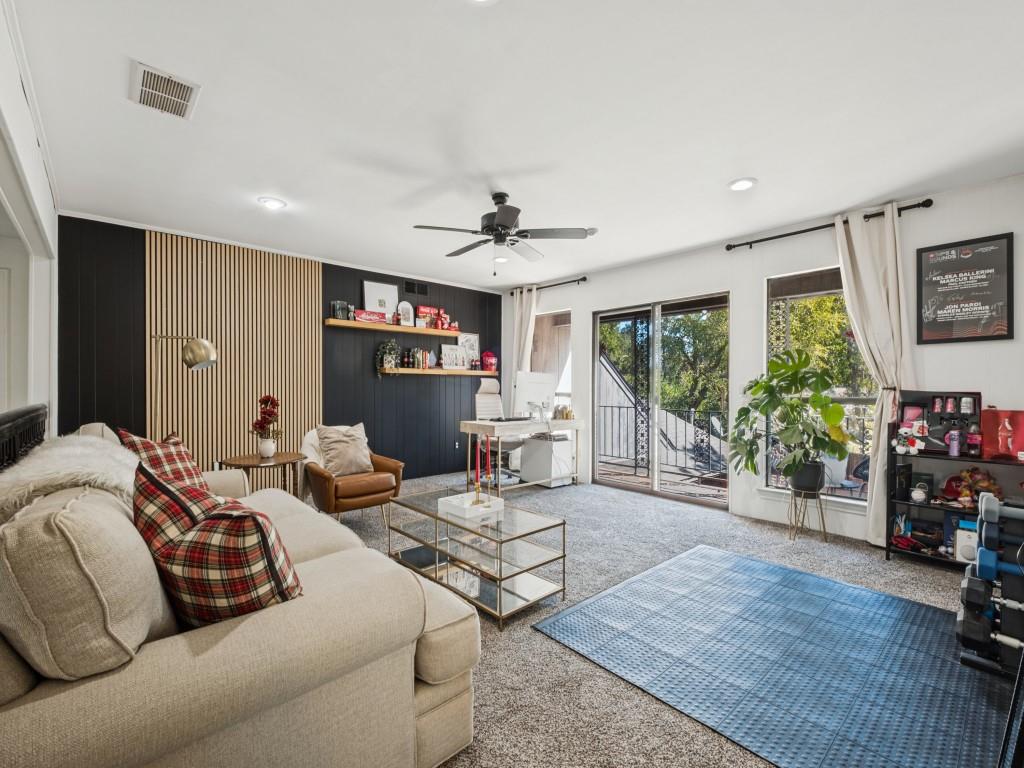 Living area featuring wood-slat accent wall, recessed lighting, ceiling fan, and sliding glass doors with exterior access Living area featuring wood-slat accent wall, recessed lighting, ceiling fan, and sliding glass doors with exterior access