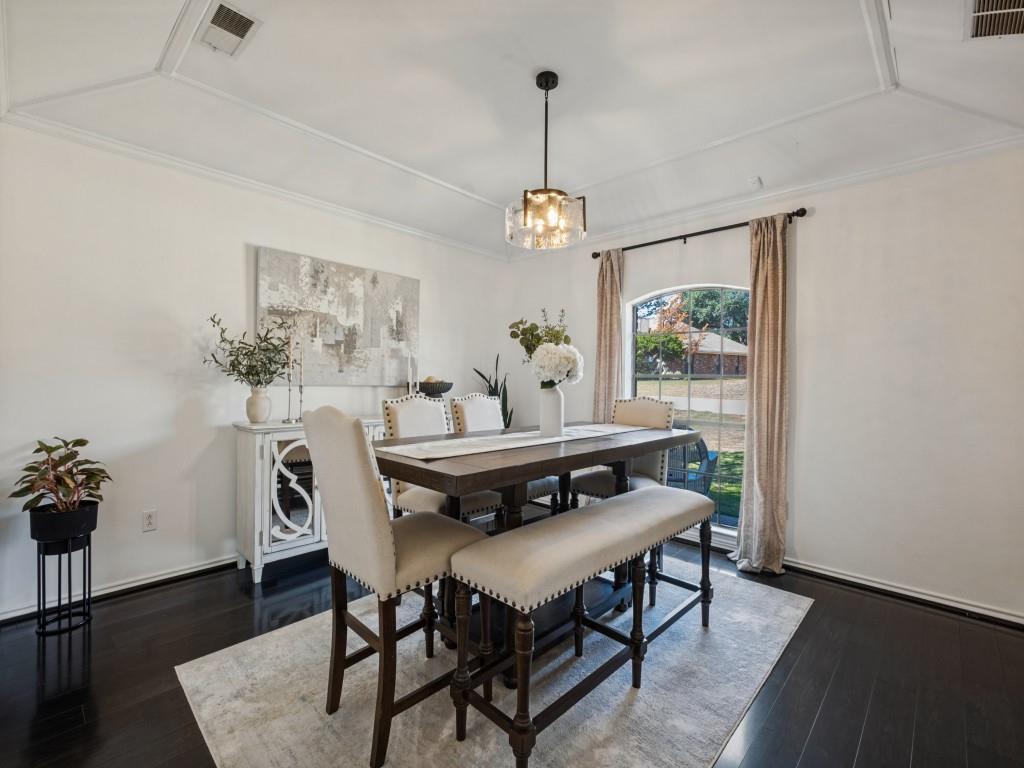 Tray ceiling, dark wood-finish flooring, and arched window with a metal-framed pendant light fixture