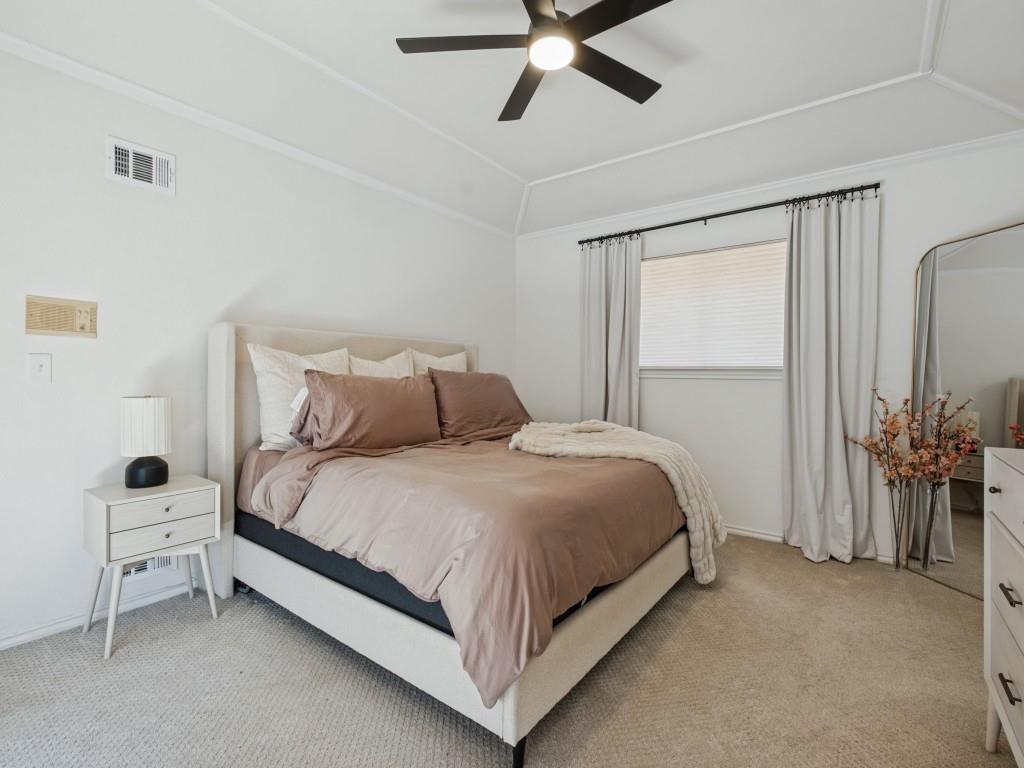 Vaulted ceilings, neutral carpeting, and a matte black ceiling fan with integrated lighting