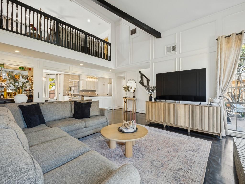 Vaulted ceilings with exposed structural beam, floor-to-ceiling decorative wall paneling, second-level balcony with black railing, and dark hardwood flooring Vaulted ceilings with exposed structural beam, floor-to-ceiling decorative wall paneling, second-level balcony with black railing, and dark hardwood flooring