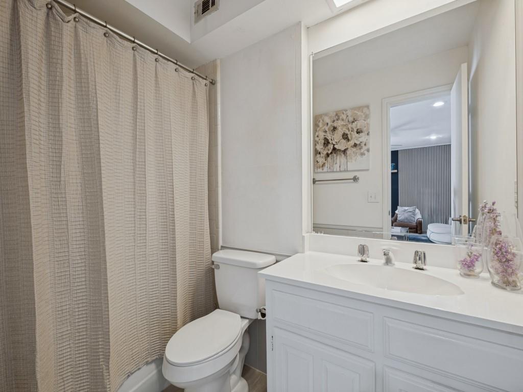 White vanity with a solid-surface countertop and integrated oval sink, paired with a full-width vanity mirror and chrome-finish hardware