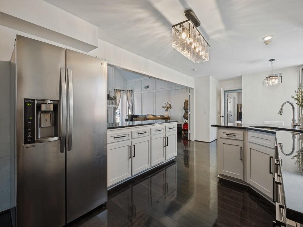 Kitchen featuring white shaker-style cabinetry with matte black hardware, dark stone countertops, stainless steel side-by-side refrigerator, recessed lighting, and wood-finish flooring