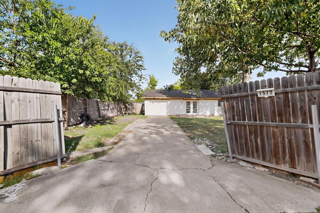 The driveway at the back of the house leading to the garage, bordered by a wooden fence on either side.