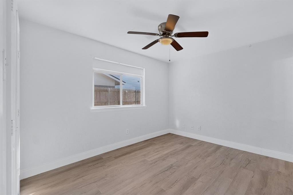 Primary bedroom featuring wood-finish flooring, a ceiling fan with light fixture, and a sliding window