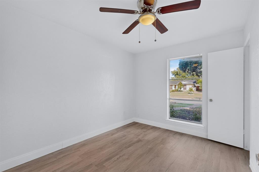 Bedroom featuring wood-finish flooring, smooth-finish walls, a single-hung window, and an integrated ceiling fan with light fixture