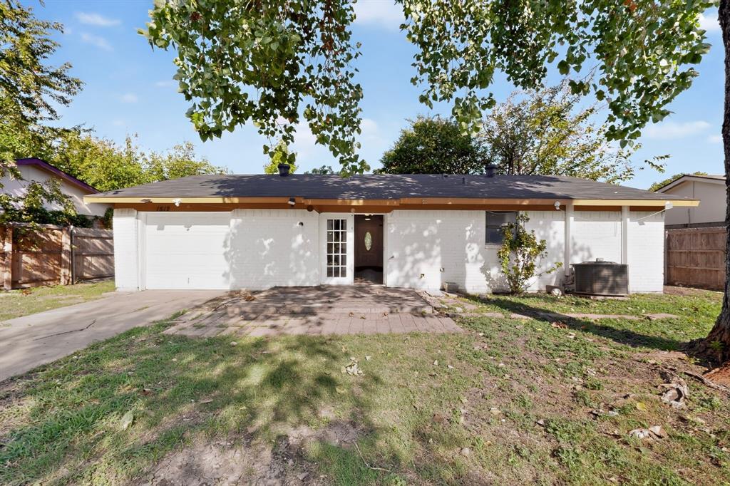 Single-story residence featuring white painted brick exterior, attached garage, paver patio, and multi-pane entry door