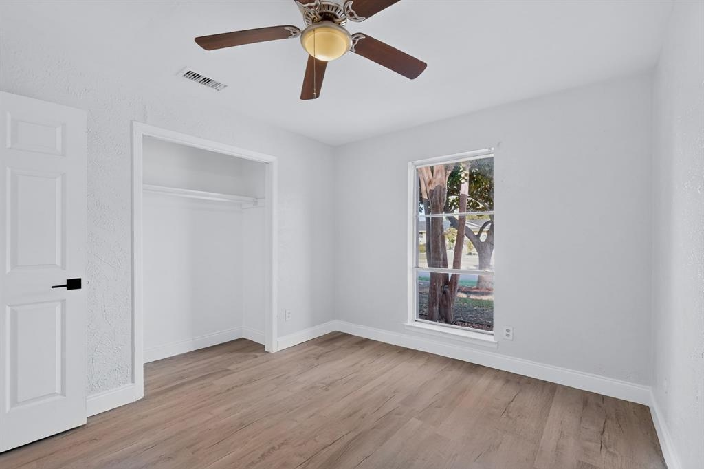 Primary bedroom featuring wood-finish flooring, a ceiling fan with integrated lighting, a reach-in closet, and a single-pane window