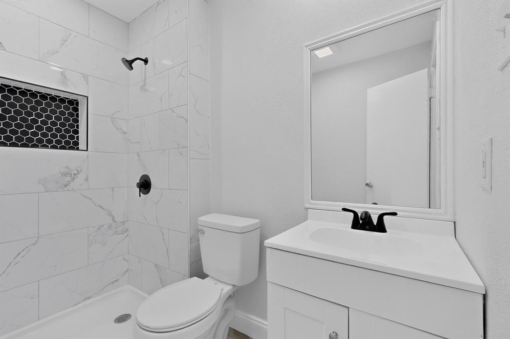 Bathroom featuring a shower with white large-format tile, a black hexagonal tile inset, and a matte black shower fixture