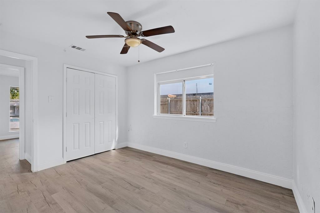 Primary bedroom featuring wood-finish flooring, a ceiling fan with integrated lighting, dual-panel closet doors, and a sliding window