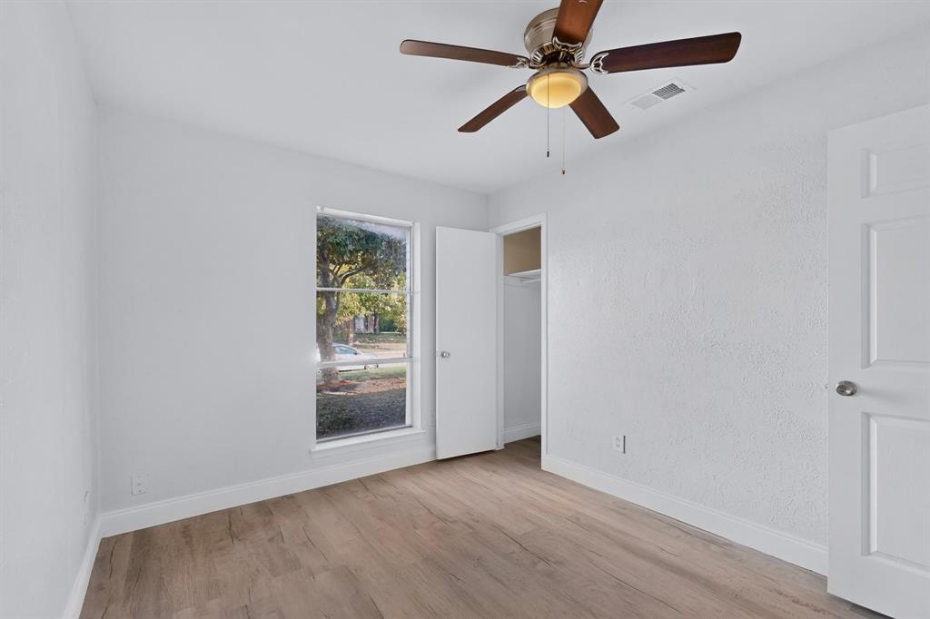 Bedroom featuring wood-finish flooring, textured walls, a single-hung window, a ceiling fan with integrated light fixture, and a built-in closet