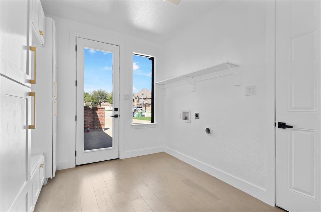 Built-in white cabinetry with gold-tone hardware, wood-finish flooring, full-light door, and a single window