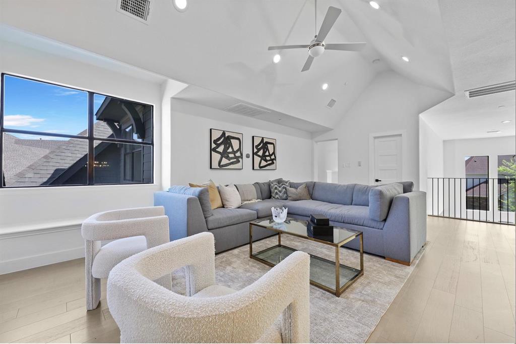 Vaulted ceiling featuring a ceiling fan and recessed lighting, light wood-finish flooring, and a black metal railing