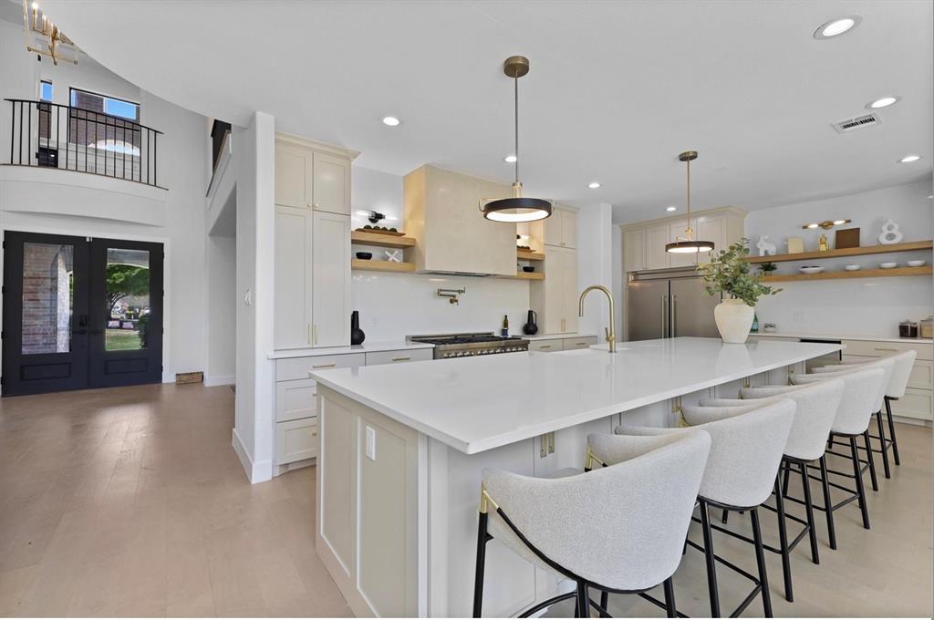 Spacious kitchen with a large central island, integrated appliances, and open shelving Spacious kitchen with a large central island, integrated appliances, and open shelving