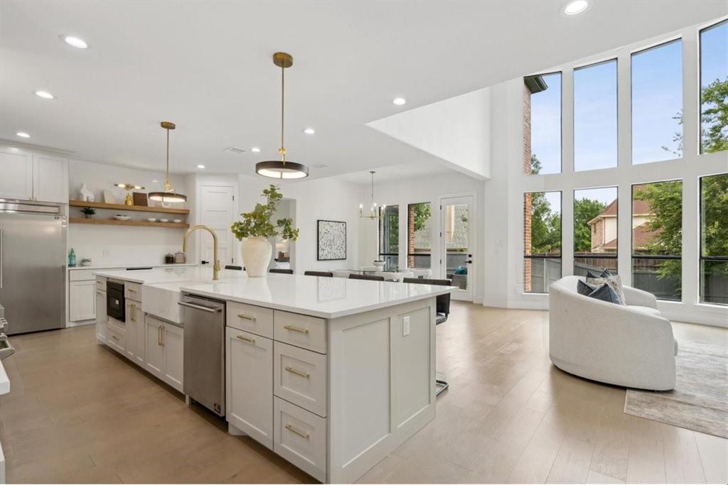 Gourmet kitchen featuring a large island with a farmhouse sink, stainless steel appliances, and white cabinetry