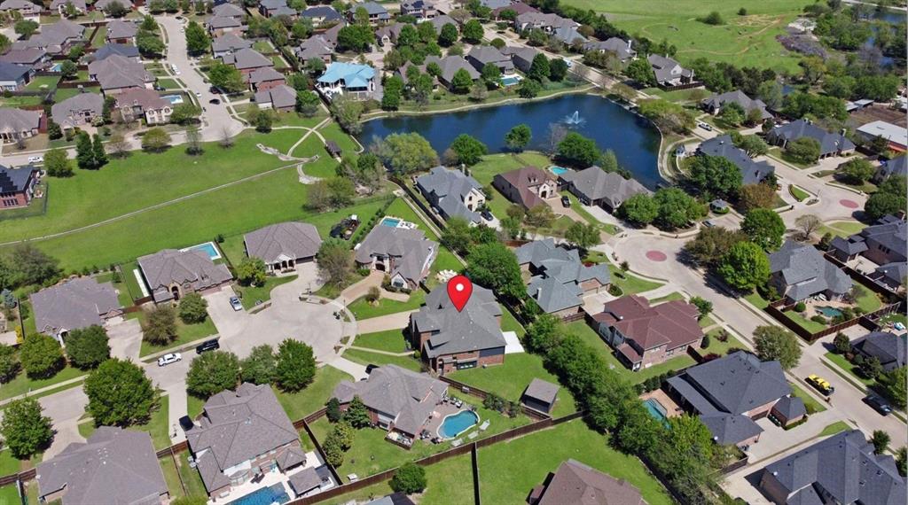 Aerial perspective of a residential neighborhood featuring established homes, mature trees, and a central pond