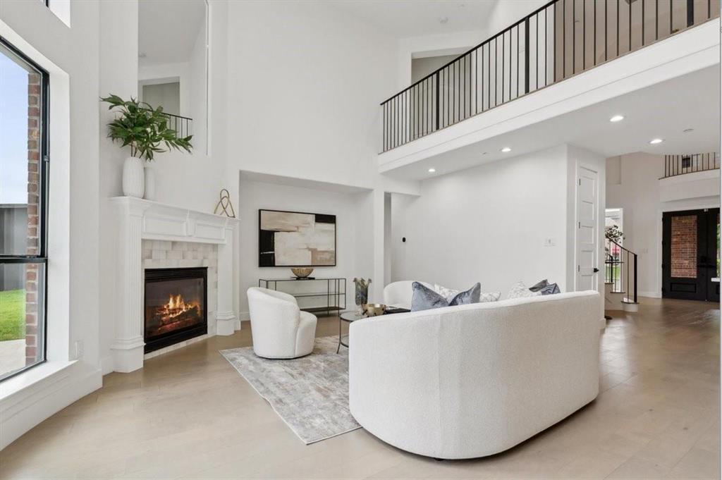 Two-story living area with high ceilings, featuring a gas fireplace with a white mantel and tile surround Two-story living area with high ceilings, featuring a gas fireplace with a white mantel and tile surround