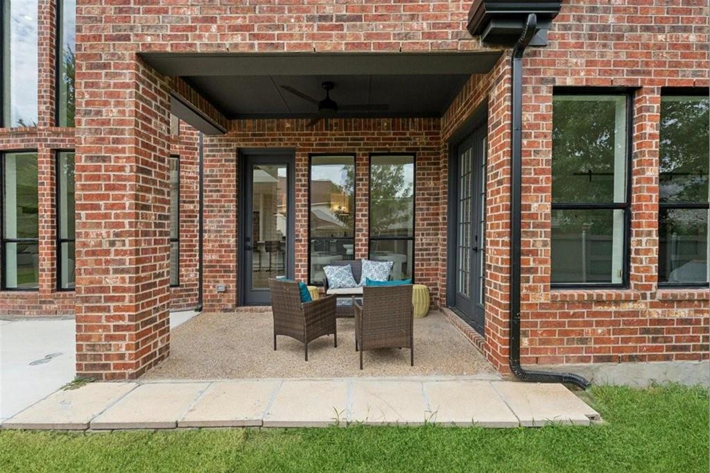 Covered outdoor patio with a ceiling fan, brick exterior, and multiple large windows