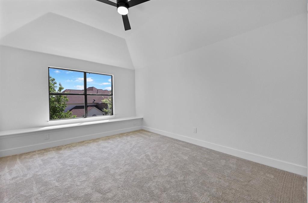 Vaulted ceiling room featuring a multi-pane window, integrated window bench, and a ceiling fan