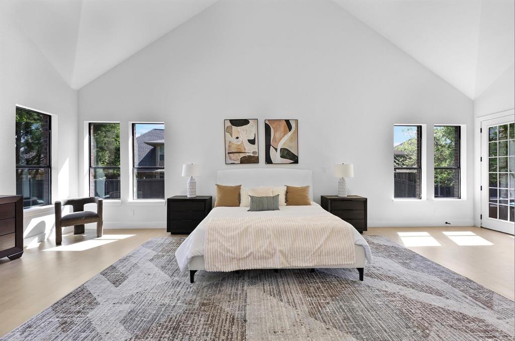 Vaulted ceiling, wood-finish flooring, multiple windows, French doors, and white walls