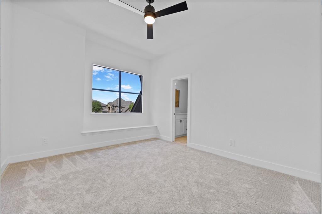 Carpeted room with a black ceiling fan, a window with exterior views, and a white interior door