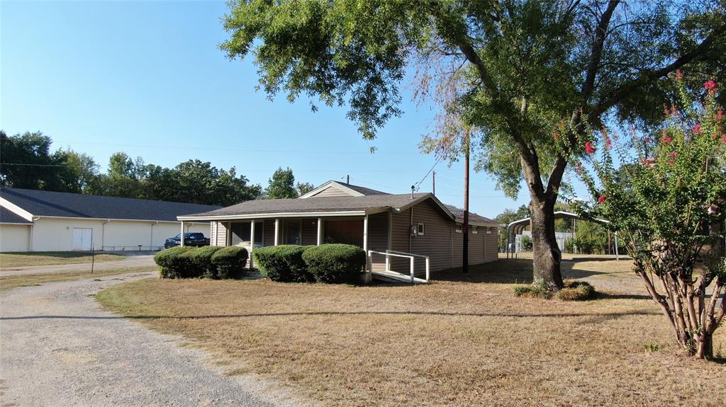 Single-story structure with a covered porch, an accessible ramp, and a gravel driveway