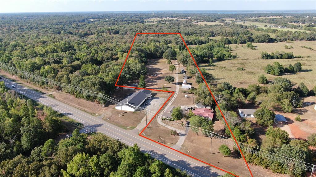 Extensive land parcel featuring a commercial building, direct road frontage, and a surrounding wooded landscape