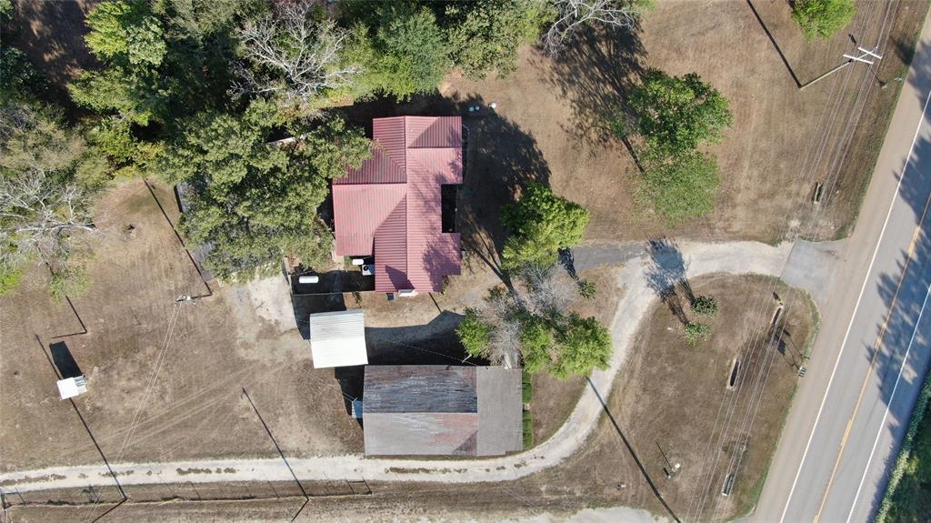 Property featuring a red-roofed structure, secondary outbuilding, and expansive cleared land
