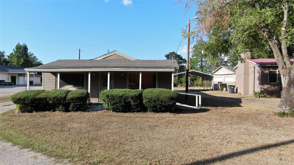 Siding exterior with a covered front porch and a carport structure