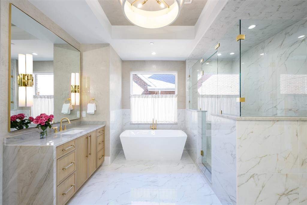 Primary bath with Venetian plaster walls, waterfall-style stone countertops and white oak soft-close cabinetry, free standing tub, walk-in shower and walk-in custom closet
