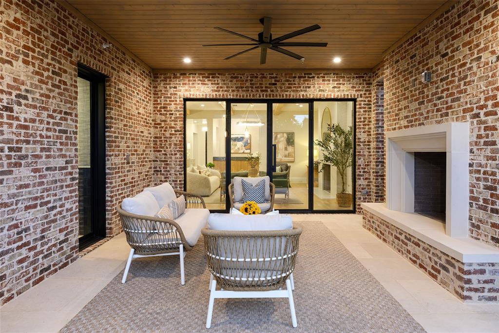 Rear loggia with large limestone slab flooring, Isokern wood-burning fireplace with raised hearth and cast stone surround, and automated screens