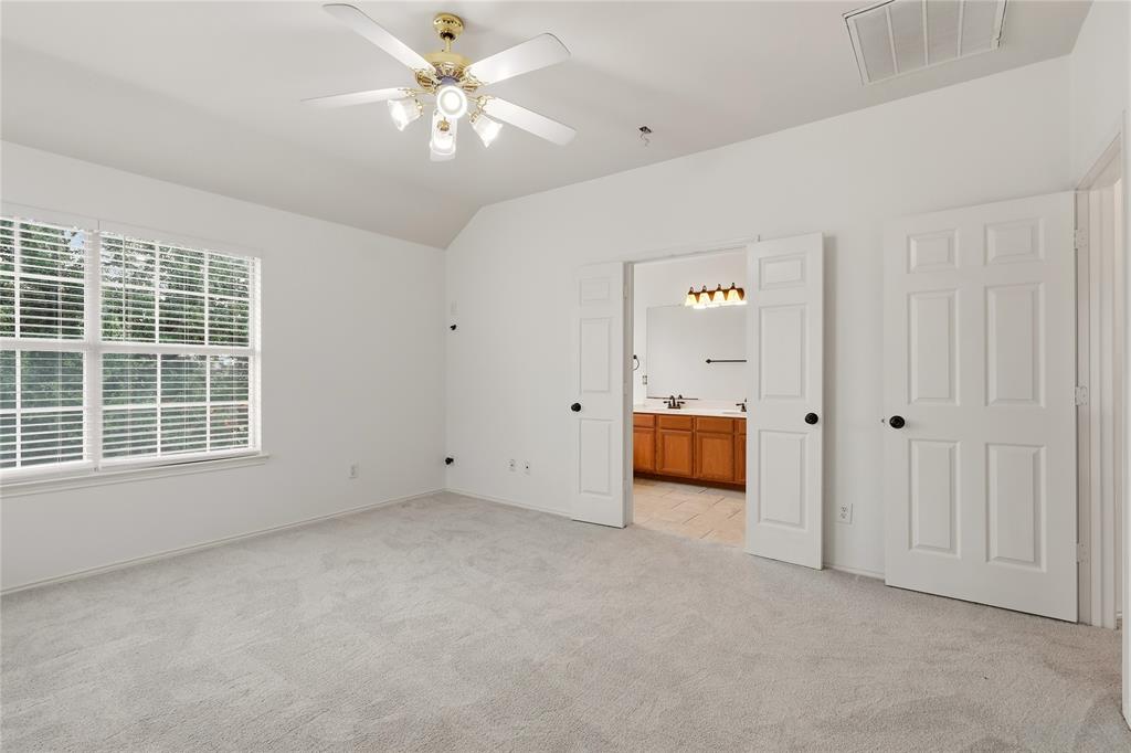 Vaulted ceiling with ceiling fan, large window with blinds, light-toned carpeting, and panel doors
