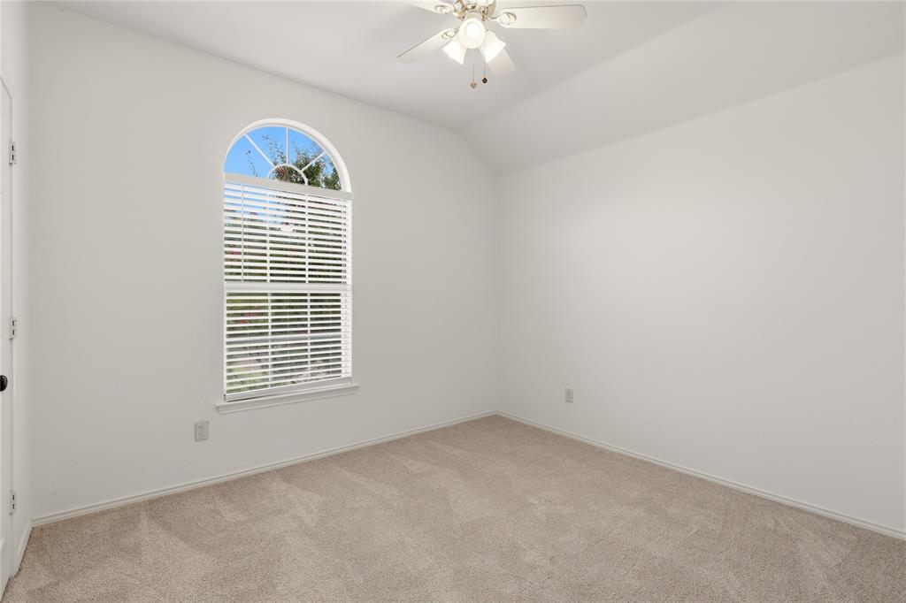 Vaulted ceiling, arched window, ceiling fan with integrated lighting, wall-to-wall carpeting, and white walls