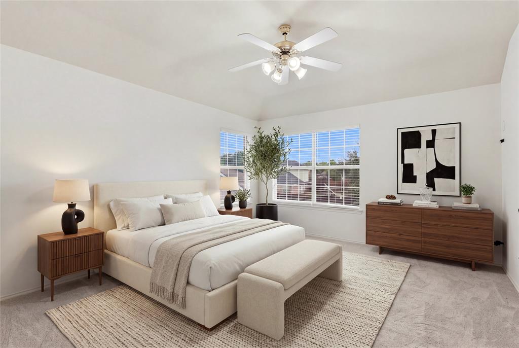 Vaulted ceiling with a ceiling fan, dual windows with blinds, and light-toned carpet flooring.  Virtually staged.