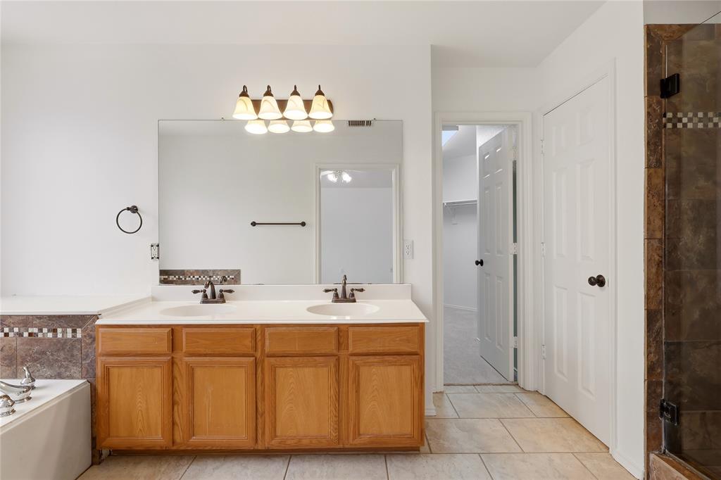 Dual vanity with integrated sinks, wood cabinetry, and a full-width mirror