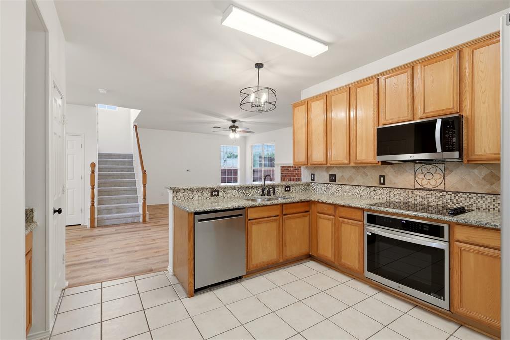 Kitchen featuring wood cabinetry, stainless steel appliances, granite countertops, and tiled flooring