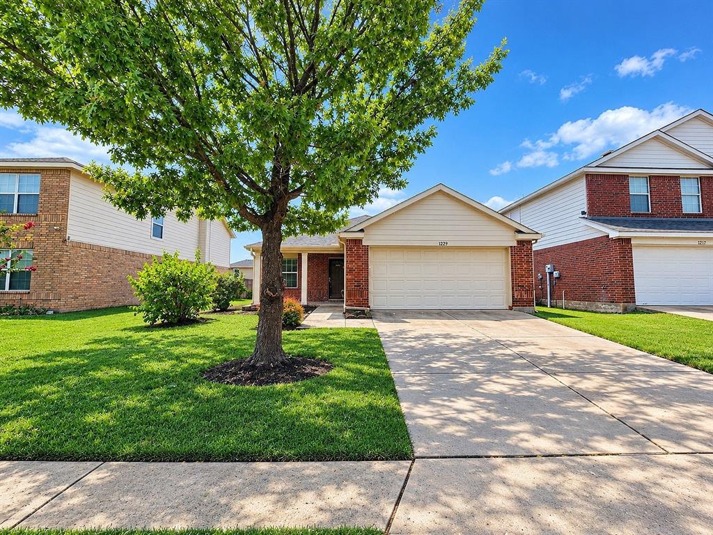 Traditional brick exterior with an attached garage, paved driveway, and mature landscaping