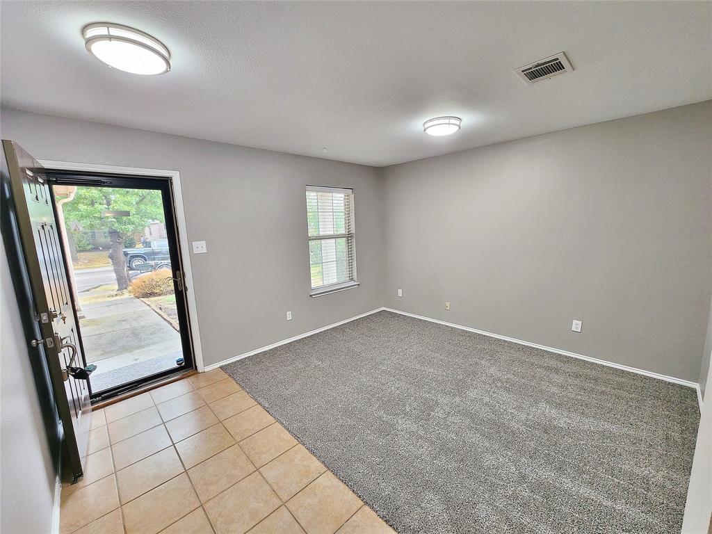 Entry area featuring tile flooring, leading to a room with neutral gray carpeting Entry area featuring tile flooring, leading to a room with neutral gray carpeting