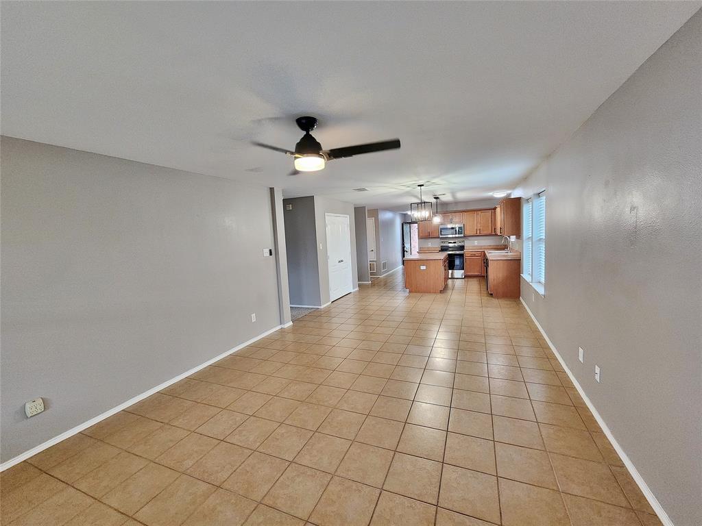 Tiled flooring throughout, ceiling fan with integrated lighting, kitchen featuring wood-finish cabinetry, stainless steel range, and a kitchen island Tiled flooring throughout, ceiling fan with integrated lighting, kitchen featuring wood-finish cabinetry, stainless steel range, and a kitchen island