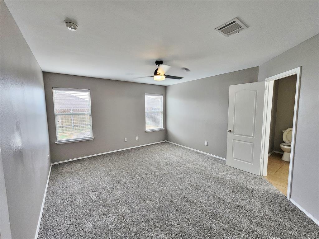Spacious room with gray carpeting, multiple windows, and a ceiling fan Spacious room with gray carpeting, multiple windows, and a ceiling fan