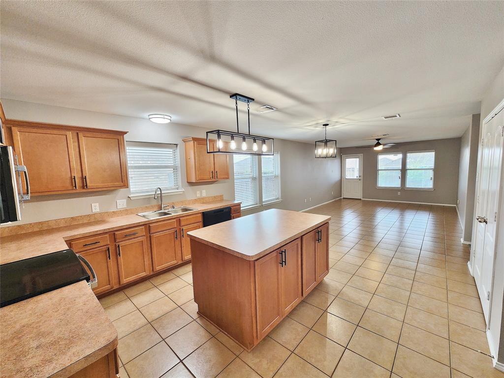 Open-concept kitchen with wood-finish cabinetry, a large center island, and tile flooring Open-concept kitchen with wood-finish cabinetry, a large center island, and tile flooring