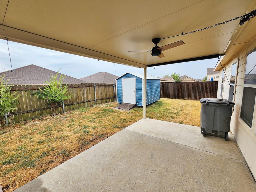 Covered patio with a ceiling fan, concrete flooring, and a storage shed
