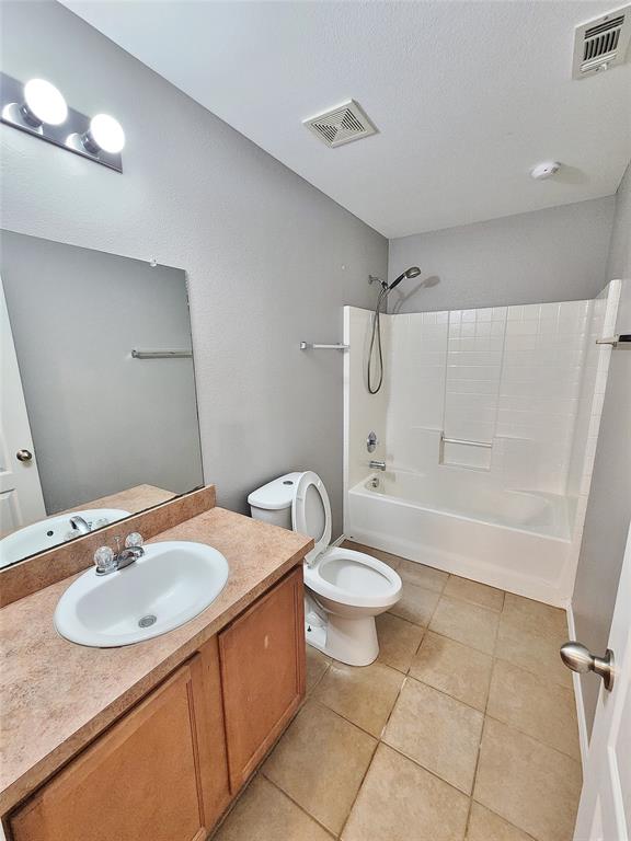 Bathroom with a wood-finish vanity, integrated sink, and a combination shower/tub