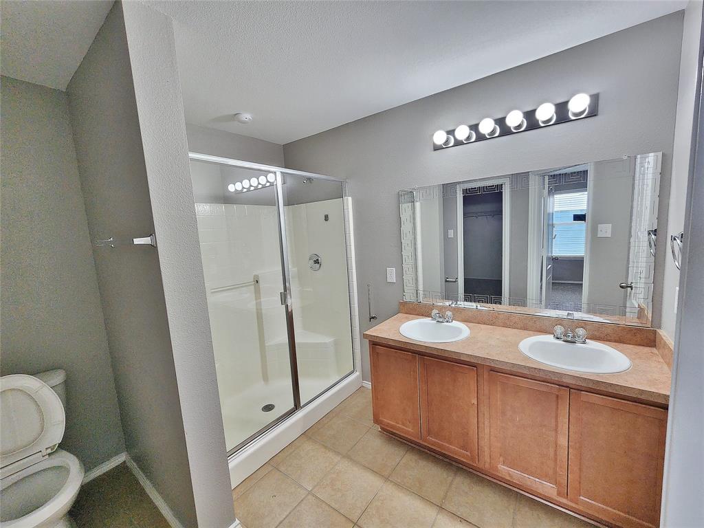 Dual vanity with integrated sinks, wood-finish cabinetry, a large mirror, and a multi-bulb light fixture